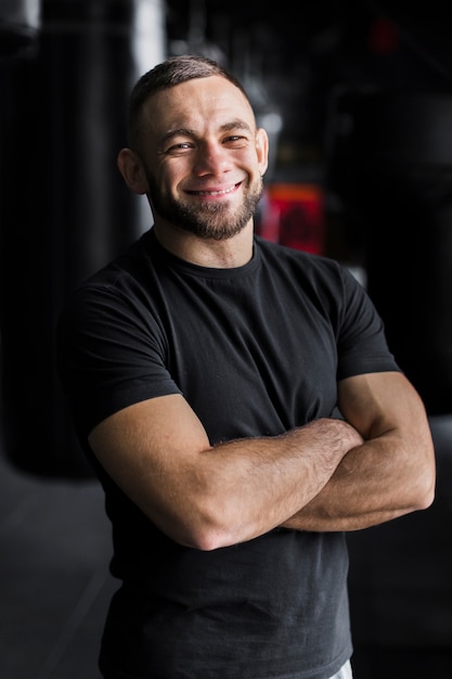 Foto gratuita sonriente boxeador masculino posando en camiseta con los brazos cruzados