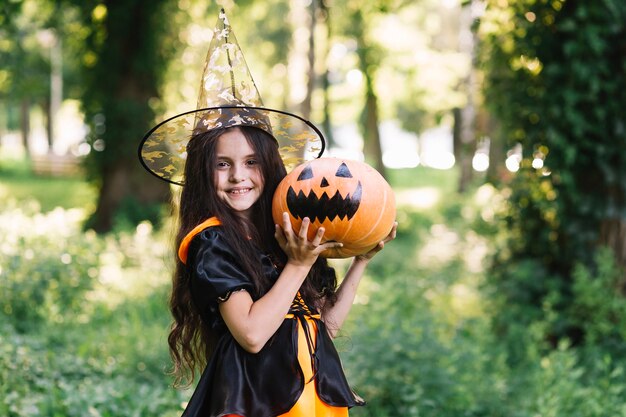 Sonriente brujita sosteniendo calabaza