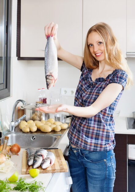 Sonriente chica rubia con pescado crudo