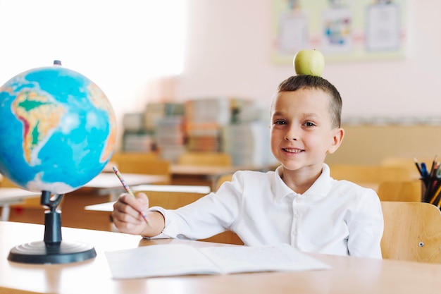 Foto gratuita sonriente colegial con manzana en la cabeza