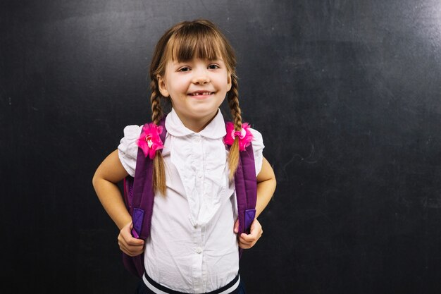 Sonriente colegiala en la pizarra