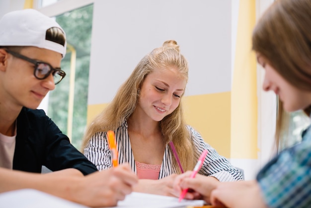 Sonriente compañeros de clase escribiendo en el escritorio