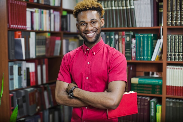 Sonriente confía en el hombre con el libro en la biblioteca