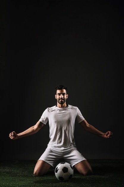 Foto gratuita sonriente deportista sentado cerca de la pelota