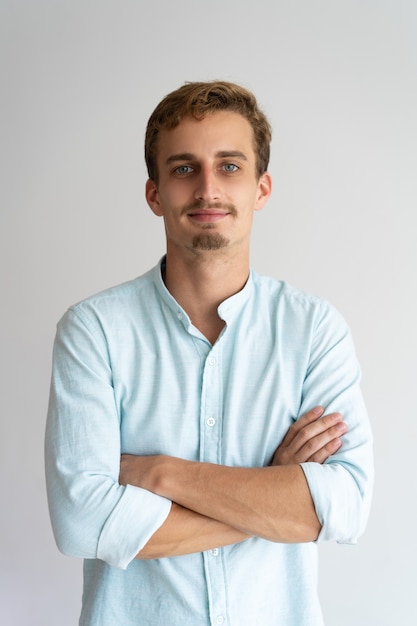 Sonriente empresario masculino con barba y bigote cruzando los brazos en el pecho