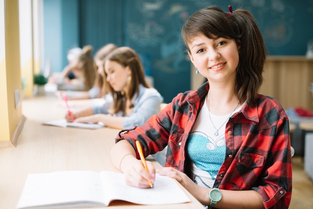 Sonriente estudiante con bloc de notas en la clase