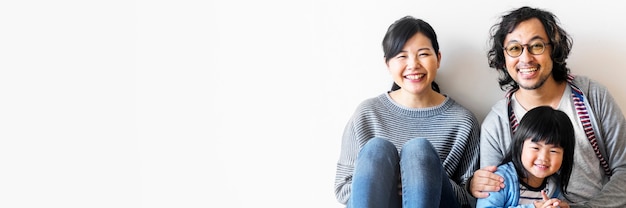 Sonriente familia asiática con una hija sentada en el suelo banner de espacio en blanco