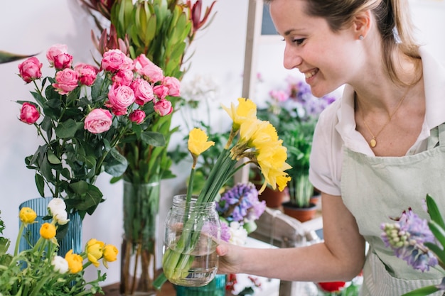Sonriente florista inspeccionando flores