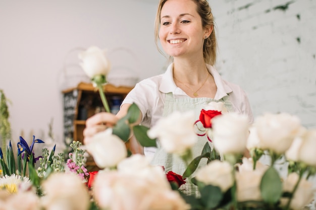 Foto gratuita sonriente florista recogiendo rosa