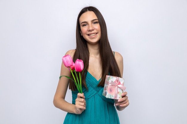 Sonriente a hermosa joven sosteniendo presente con flores