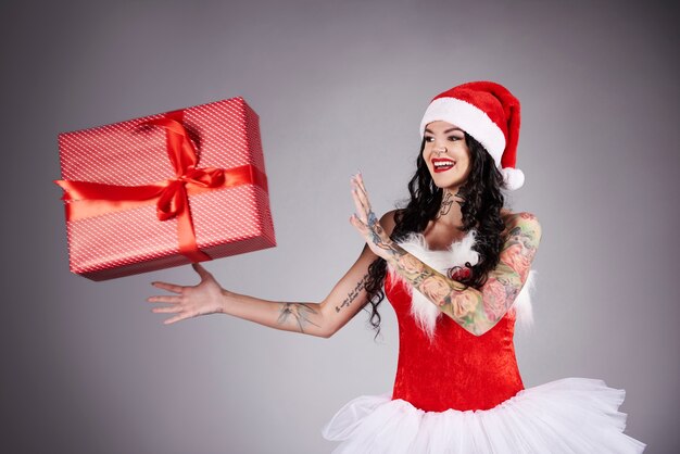 Sonriente y hermosa mujer cogiendo gran regalo de Navidad rojo