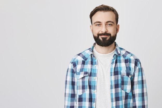 Sonriente hombre adulto guapo con barba mirando