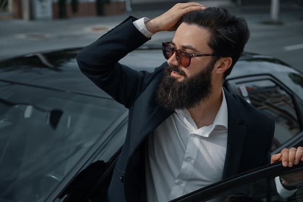 Sonriente hombre guapo con barba tocando su cabello