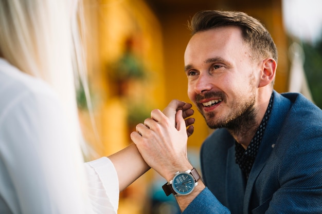 Sonriente hombre guapo con la mano de su novia