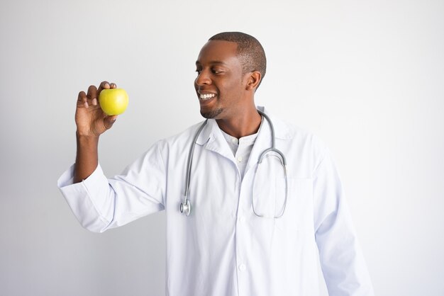 Sonriente a hombre médico negro con manzana verde.