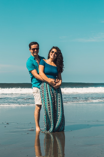 Sonriente hombre y mujer abrazando en el paseo marítimo de la playa