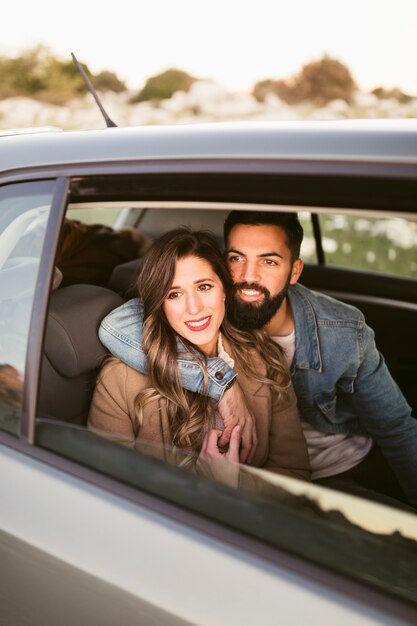 Sonriente hombre y mujer sentada en los asientos traseros