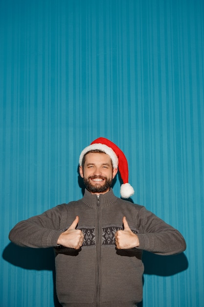 Sonriente hombre de Navidad con un gorro de Papá Noel en el fondo azul.
