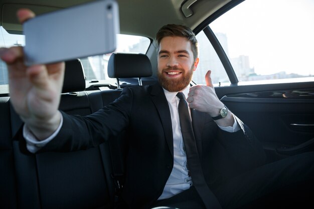 Sonriente hombre de negocios exitoso tomando selfie