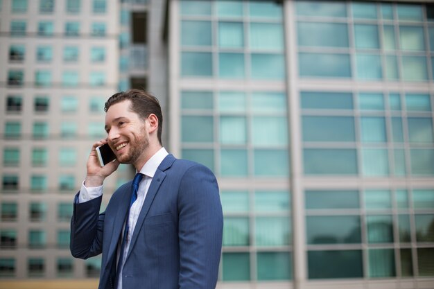 Sonriente, hombre de negocios, hablando, teléfono, afuera