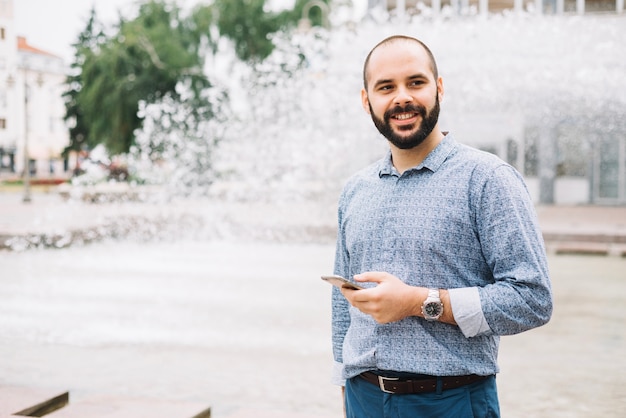 Sonriente hombre de negocios con teléfono en el centro