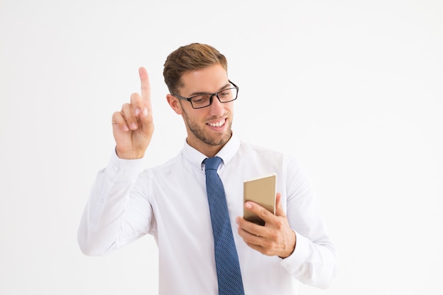 Sonriente hombre de negocios usando teléfono inteligente y levantando el dedo