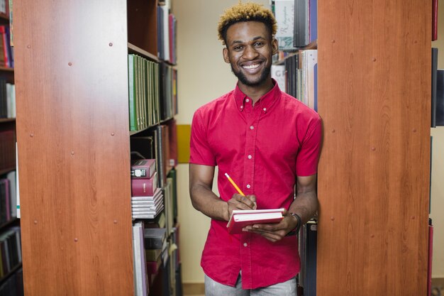 Sonriente hombre negro posando en la biblioteca