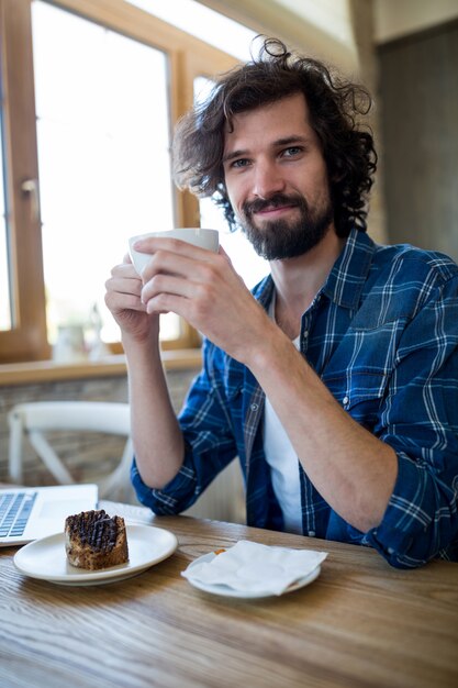 Sonriente hombre tener café y pastelería en la cafetería