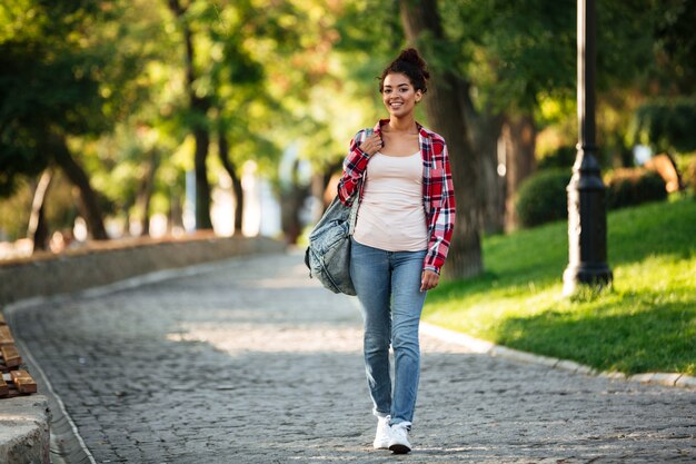 Sonriente joven africana caminando al aire libre