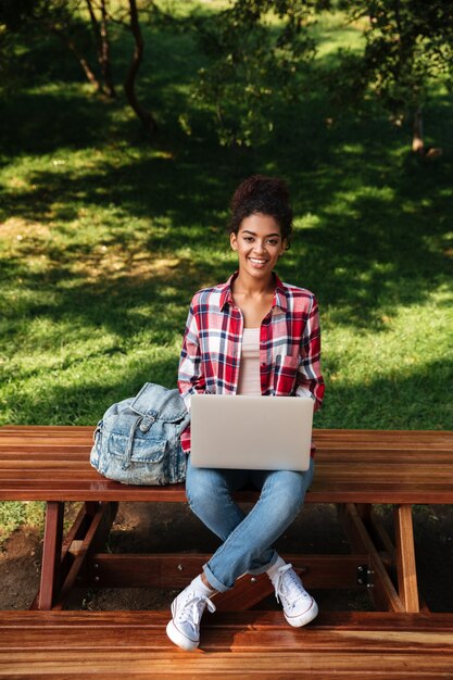 Sonriente joven africana sentada al aire libre en el parque