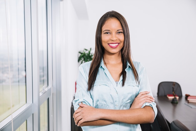 Sonriente joven afroamericana junto a la ventana