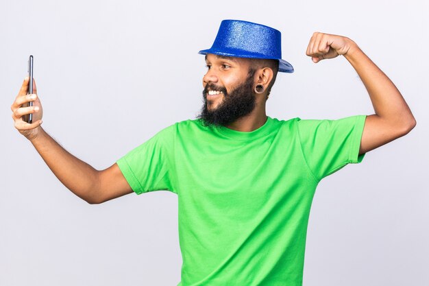 Sonriente joven afroamericano con gorro de fiesta tomar un selfie mostrando un gesto fuerte