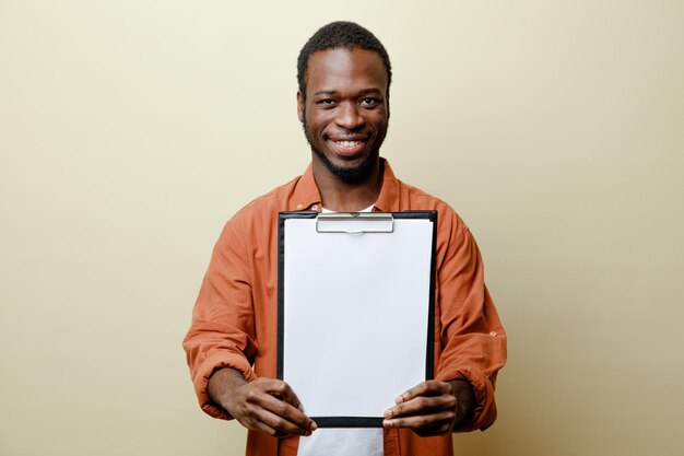 Sonriente joven afroamericano sosteniendo portapapeles aislado sobre fondo blanco.