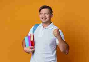 Foto gratuita sonriente joven apuesto estudiante vistiendo bolsa trasera sosteniendo libros