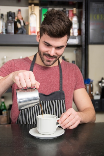 Sonriente joven barista masculino preparar café