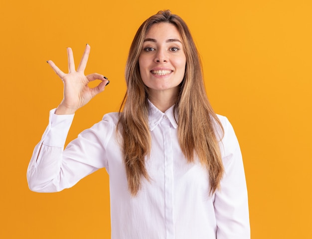 Sonriente joven bastante caucásica gestos signo de mano ok