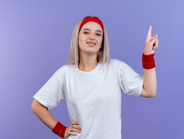 Sonriente joven caucásica deportiva con tirantes vistiendo diadema