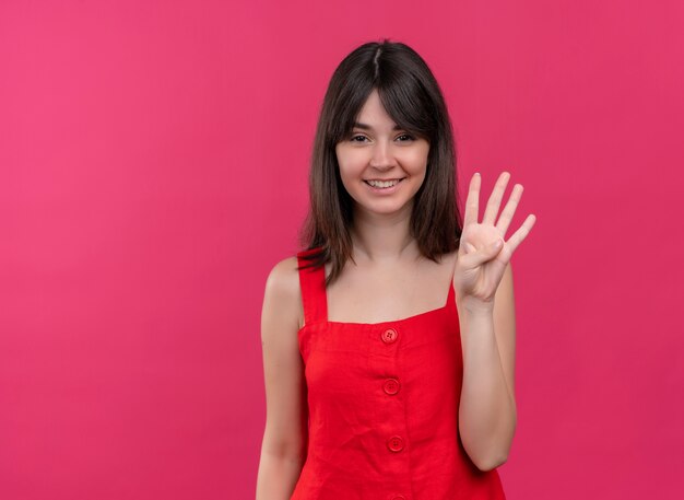 Sonriente joven caucásica muestra cuatro con los dedos sobre fondo rosa aislado con espacio de copia
