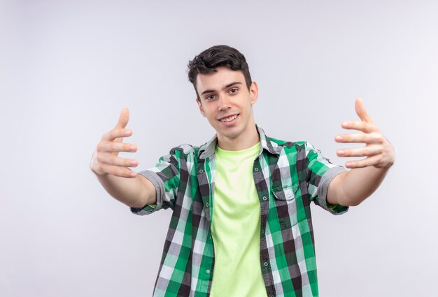 Foto gratuita sonriente joven caucásico vistiendo camisa verde fingiendo sostener algo sobre fondo blanco aislado