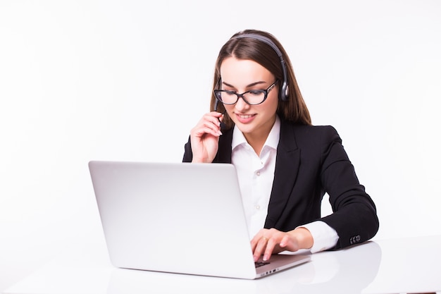 Sonriente joven chica de servicio al cliente con un auricular en su lugar de trabajo aislado en blanco