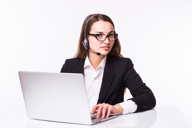 Sonriente joven chica de servicio al cliente con un auricular en su lugar de trabajo aislado en blanco