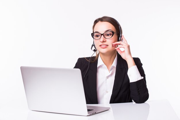 Sonriente joven chica de servicio al cliente con un auricular en su lugar de trabajo aislado en blanco