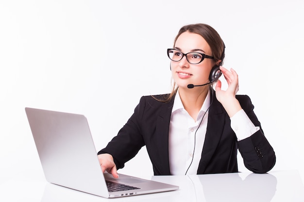 Sonriente joven chica de servicio al cliente con un auricular en su lugar de trabajo aislado en blanco