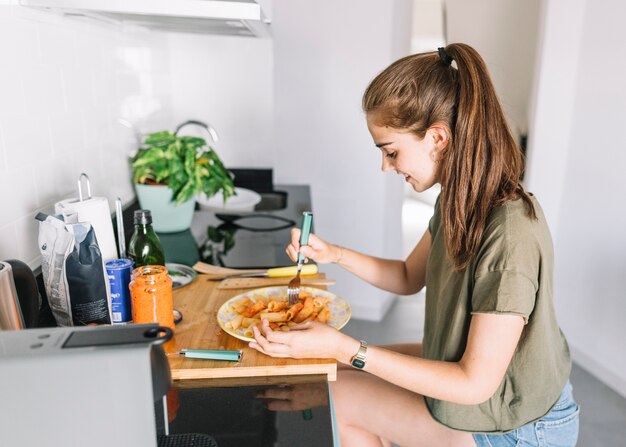 Sonriente joven comiendo pasta en el desayuno