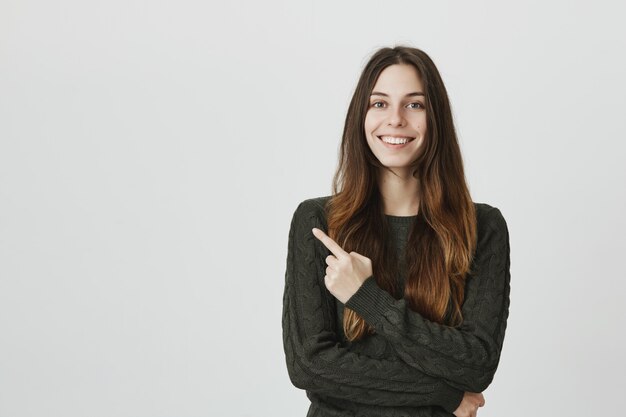 Sonriente joven dedo acusador esquina superior izquierda, mostrando publicidad