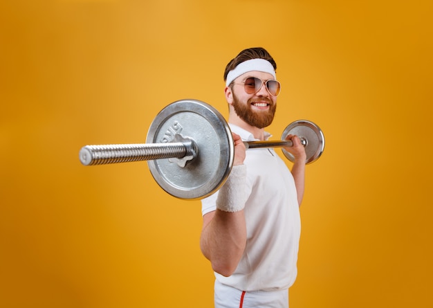 Sonriente joven deportista hacer ejercicios deportivos con barra