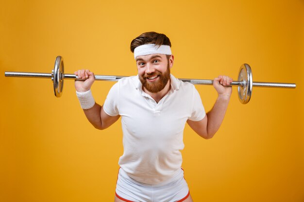 Sonriente joven deportista hacer ejercicios deportivos con barra