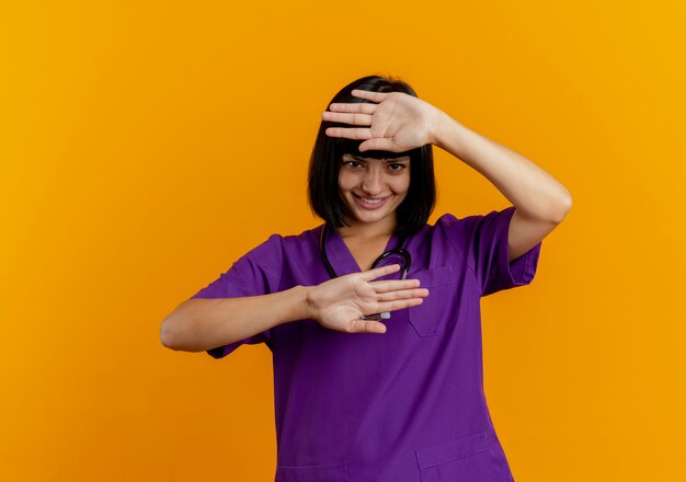 Sonriente joven doctora morena en uniforme con estetoscopio