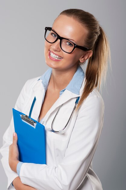 Foto gratuita sonriente joven doctora con portapapeles azul