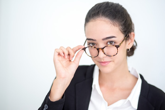 Sonriente joven empresaria tocando las gafas